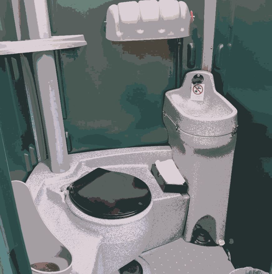 Clean porta potty interior showing the toilet, urinal, sanitizer and paper holder